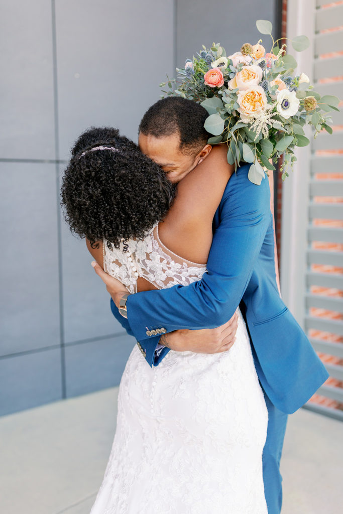The bride and groom (who is in a bright blue suit) emotionally embrace after their first look. 