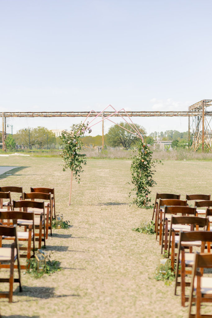 The ceremony location, complete with industrial view, floral arch, and natural wood chairs. 